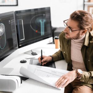 3d artist using blueprint with graphics tablet and computers while working on project of 3d design